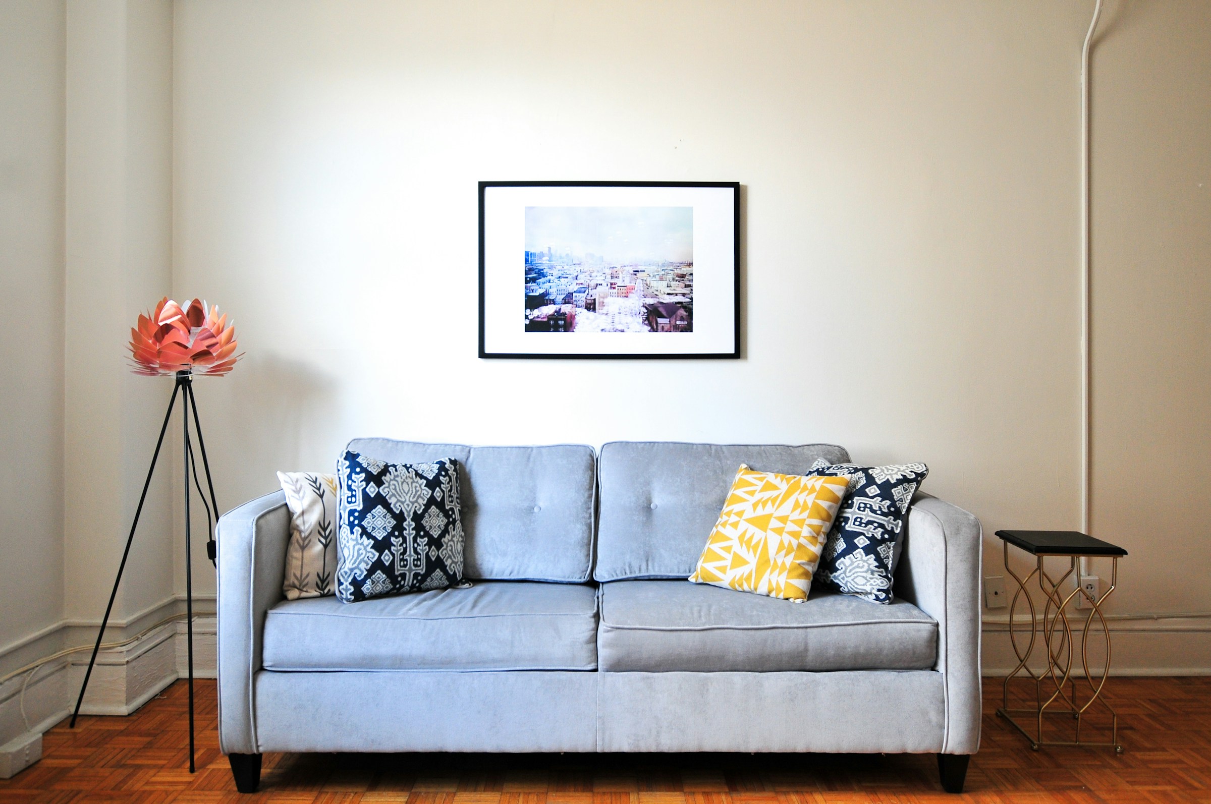 Bright, freshly-cleaned living room with grey sofa and yellow accent pillow